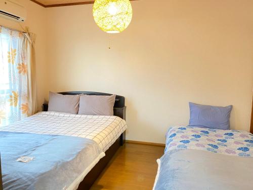 a bedroom with two beds and a chandelier at kASUMI-an4 in Kumamoto