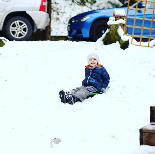 a young child sitting in the snow at Chata Pod Lasem in Poręba