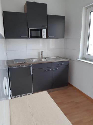 a small kitchen with a sink and a microwave at Danilos Boardinghouse in Weinheim