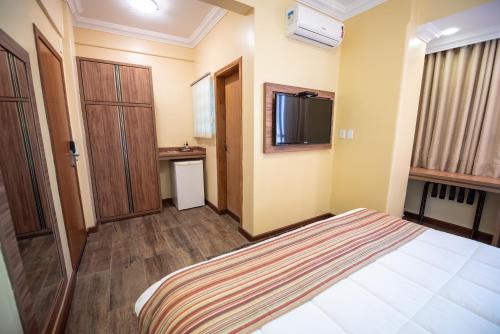 a hotel room with a bed and a window at Hotel Alles Blau in Pelotas