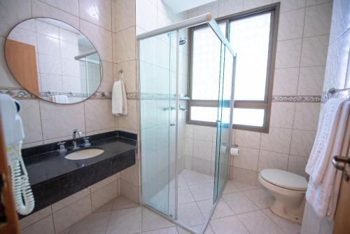 uma casa de banho com um lavatório e uma cabina de duche em vidro. em Hotel Alles Blau em Pelotas