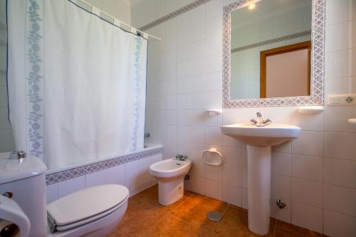 a bathroom with a sink and a toilet and a mirror at Chalet Pedro II in Conil de la Frontera