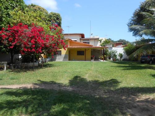 a house with a tree with red flowers in the yard at Temporada Maria Farinha in Paulista