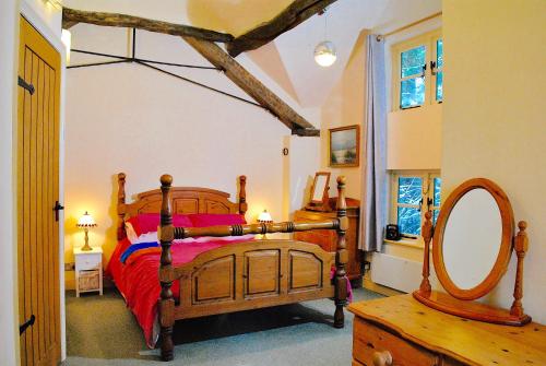a bedroom with a wooden bed and a mirror at Squirrel Barn in Milwich