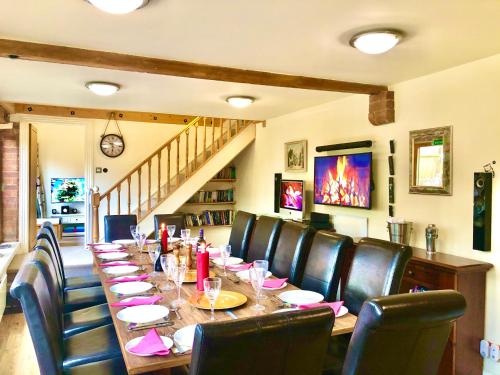 a dining room with a long table and leather chairs at Squirrel Barn in Milwich