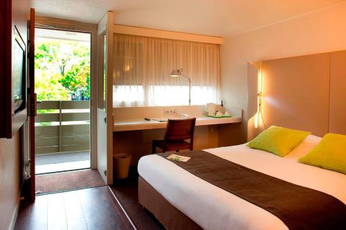 サランにあるHôtel Campanile Orléans Nord - Saranのベッドとデスクが備わるホテルルームです。