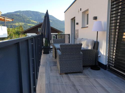 a balcony with chairs and a table and an umbrella at Casa Vierthaler in Scheffau am Wilden Kaiser