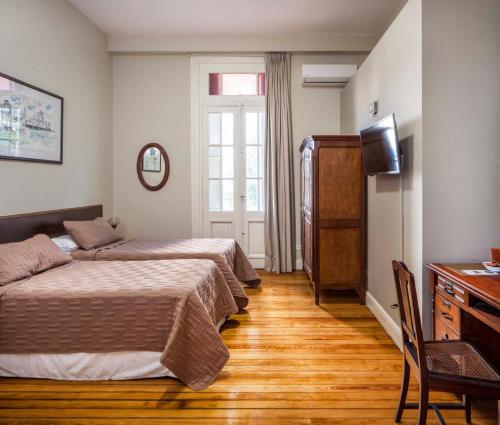 a bedroom with two beds and a desk and a television at Bar de Fondo Suites in Buenos Aires