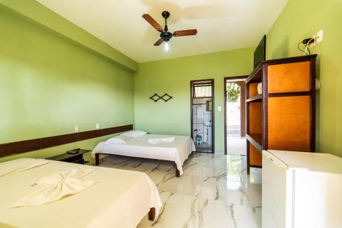 a bedroom with two beds and a ceiling fan at Pousada Doce Rio in Três Marias