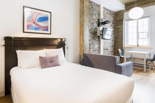 a bedroom with a bed and a chair and a table at Les Lofts de Buade - Par Les Lofts Vieux-Québec in Quebec City