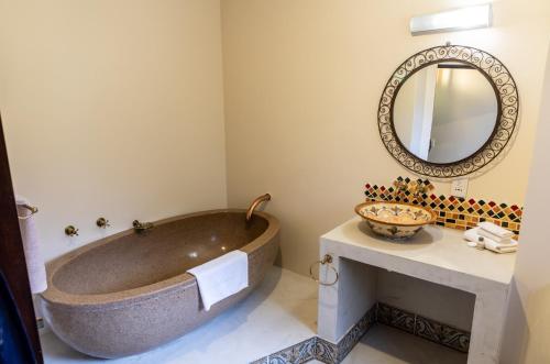 a bathroom with a large tub and a mirror at Far Hills Country Hotel in George