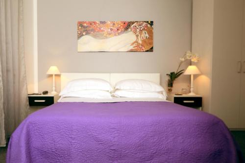 a purple bed with white pillows and a painting at Villa Pirandello in Rome