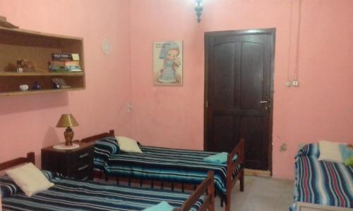 duas camas num quarto com paredes cor-de-rosa e uma porta em POSADA em Minas