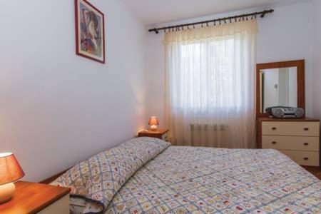 a bedroom with a bed and a dresser and a mirror at Apartment Quiet Getaway in Koromačno