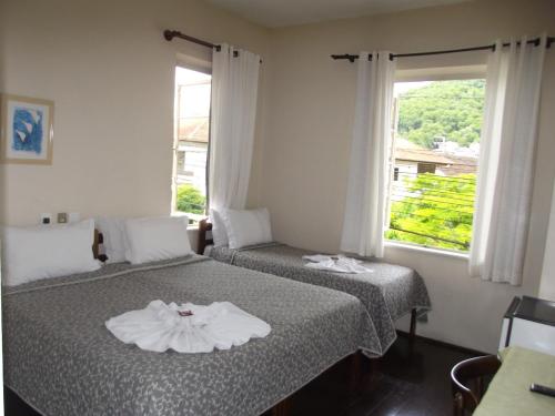 two beds in a room with a window at Pousada Max Pomerode in Pomerode