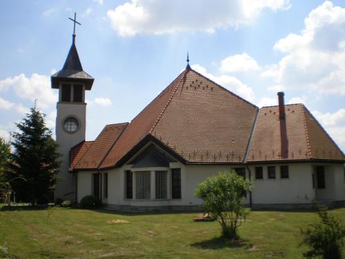a church with a steeple and a clock tower at Elvira Vendégház in Kisbodak