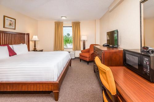 Cette chambre comprend un lit et une télévision à écran plat. dans l'établissement Days Inn & Suites by Wyndham Lake Okeechobee, à Okeechobee