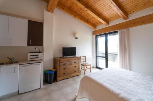a bedroom with a bed and a kitchen with a window at Estudios Ermitabarri in Zeberio