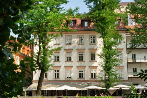 a large white building with trees in front of it at Julija&Robert's Riverview Apartments and Rooms in Ljubljana