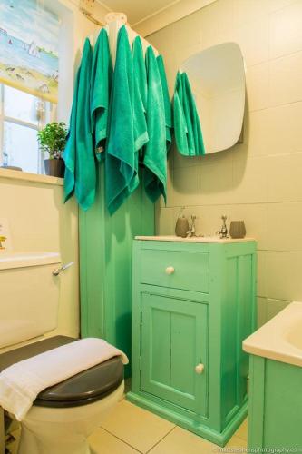 a green bathroom with a toilet and a sink at Seafront Apartment with Garden in Brighton & Hove