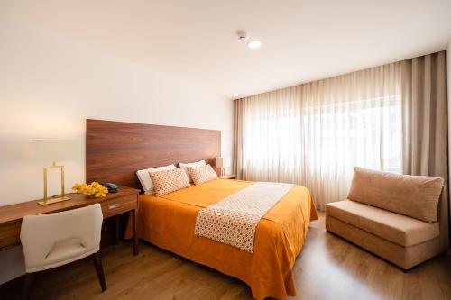 a bedroom with a bed and a desk and a chair at Hotel Nossa Senhora da Paz in Fátima