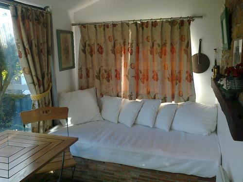 - un canapé avec des oreillers dans une chambre avec une fenêtre dans l'établissement GIVERNY COTTAGE, à Saint-Coulomb