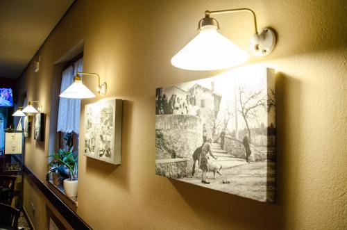 a hallway with two lights and pictures on the wall at Al Fogolâr Rooms & Osteria with Saunaland in Tolmezzo