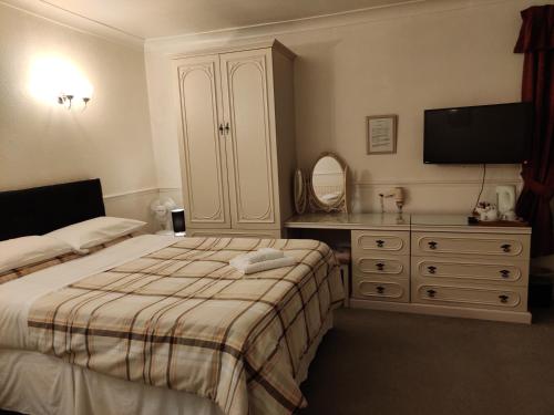 a bedroom with a bed and a dresser and a television at Arundel Park Hotel in Arundel
