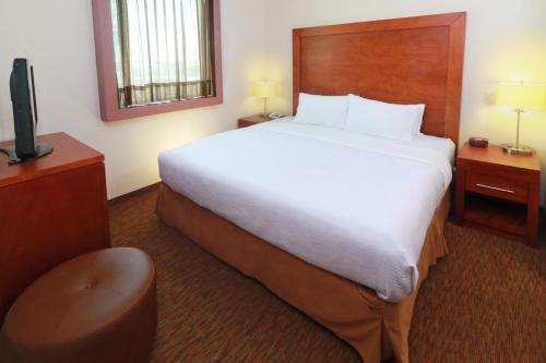 a hotel room with a large bed and a television at Staybridge Suites Queretaro by IHG in Querétaro