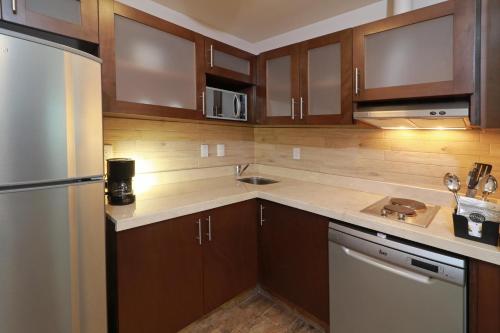 a kitchen with wooden cabinets and a stainless steel refrigerator at Staybridge Suites Queretaro by IHG in Querétaro