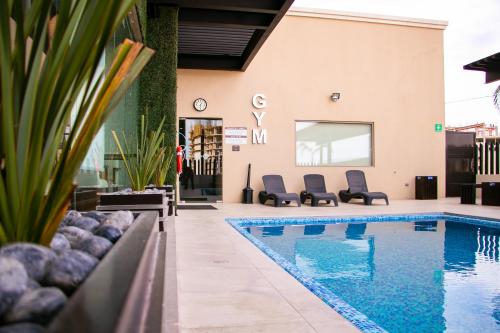 a swimming pool with chairs next to a building at Best Western Plus Chihuahua Juventud in Chihuahua