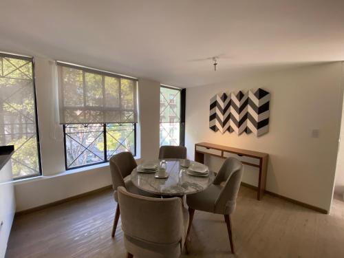 a dining room with a table and chairs and windows at Casa Londres in Mexico City