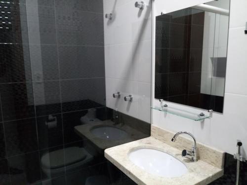 ein Bad mit einem Waschbecken und einem Spiegel in der Unterkunft Jacarandá Palace Hotel in Teixeira de Freitas