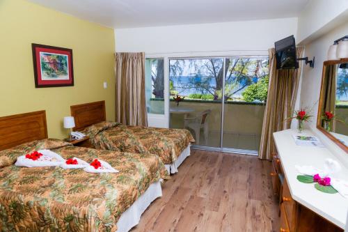 um quarto de hotel com duas camas e uma varanda em Crown Point Beach Hotel em Crown Point