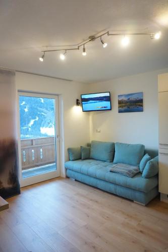 uma sala de estar com um sofá azul e uma grande janela em Ferienwohnung Wipptalblick em Navis