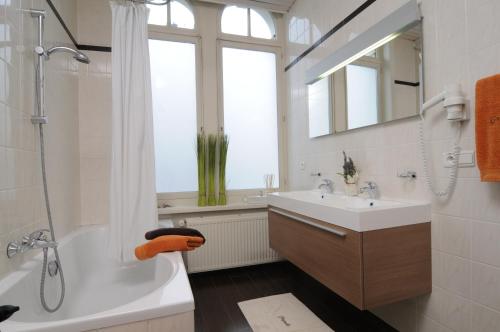 bagno con vasca, lavandino e doccia di Hotel Grupello a Geraardsbergen