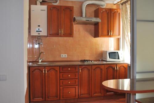 uma cozinha com armários de madeira e um micro-ondas em Аппартаменты на проспекте Александра Поля Кирова 127 em Dnipro