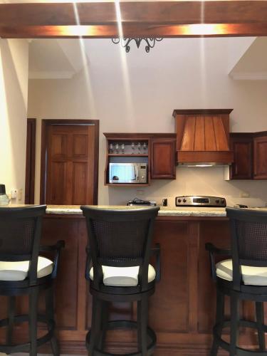 a kitchen with wooden cabinets and bar stools at Palm Coast Luxury Rentals in Esterillos Este