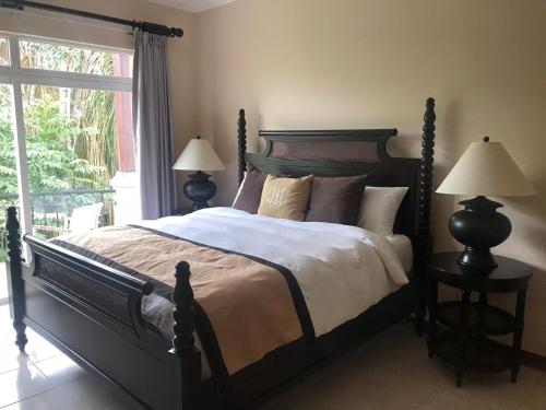 a bedroom with a bed with two lamps and a window at Palm Coast Luxury Rentals in Esterillos Este