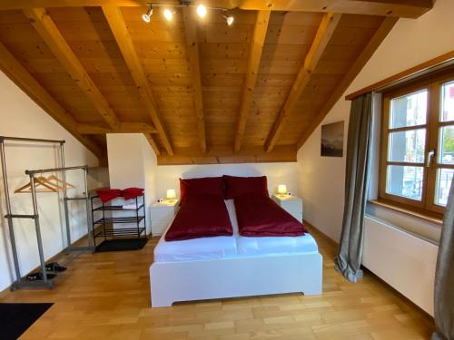 Schlafzimmer mit einem weißen Bett und roten Kissen in der Unterkunft Atelier 67 in Oberschan