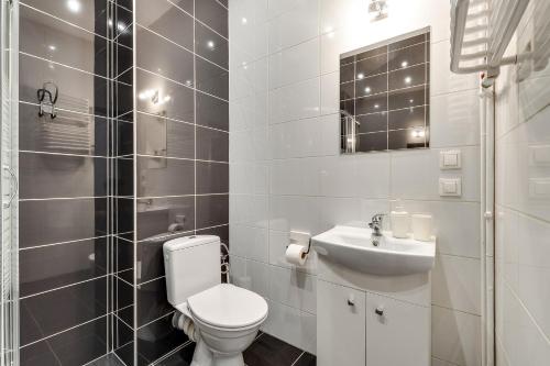 a white bathroom with a toilet and a sink at KATO Apartamenty Moniuszki in Katowice