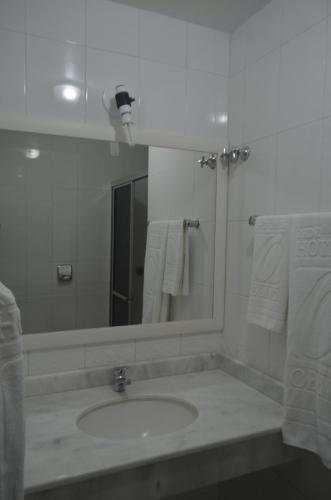 a bathroom with a sink and a mirror and towels at Hotel Obino São Borja in São Borja