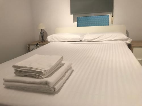 Una cama con sábanas blancas y toallas. en Ático Port La Ràpita, en Sant Carles de la Ràpita