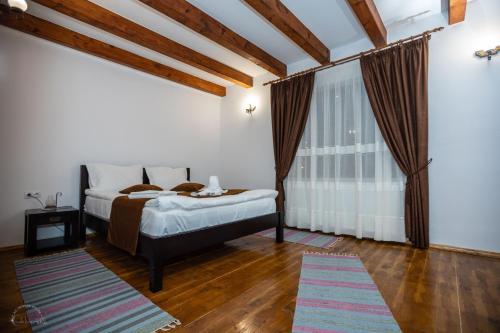 a bedroom with a bed and a large window at Domeniul Poiana Ursului in Dumbrăveni
