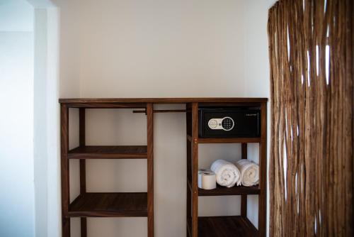 a wooden book shelf with a clock and towels at El Alquimista Yoga Spa in Zipolite