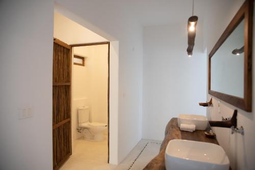 a bathroom with a toilet a sink and a mirror at El Alquimista Yoga Spa in Zipolite