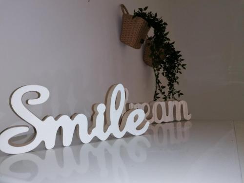 a white smile sign on a wall with a plant at Apartmani "Mary" in Grebaštica