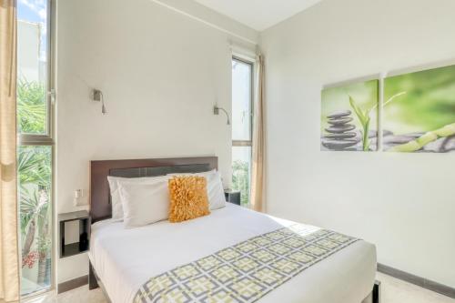 1 dormitorio con cama blanca y ventana grande en Klem Residence, en Playa del Carmen