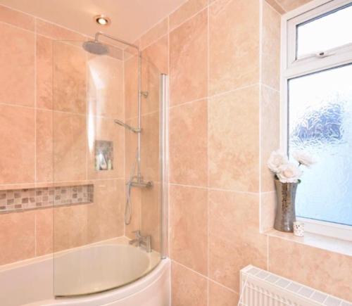 a bathroom with a tub and a shower with a window at The Beach House - Fully refurbed March 2024 in Oystermouth