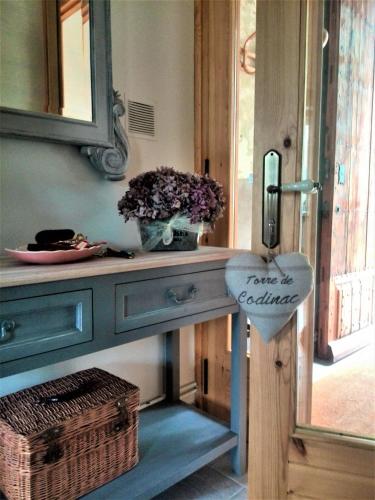 a blue console table with a mirror and flowers on it at Torre de Codinac in Sant Pere de Torelló